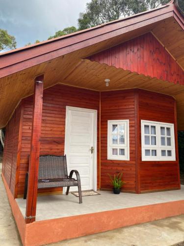 a bench sitting on the porch of a wooden shed at Chalés Canto da Serra in Monte Verde