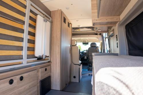 a camper van with a bed and a window at Van Del Sol - Stay where it moves you with Sunny in San Juan