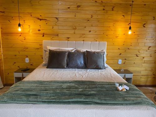a bedroom with a large bed with wooden walls at Chalés Canto da Serra in Monte Verde