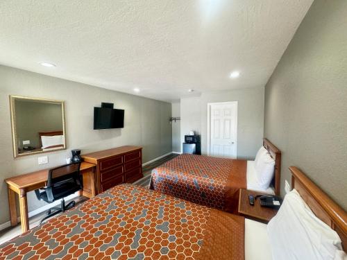 Habitación de hotel con 2 camas y escritorio en Villa Court Inn Oroville, en Oroville