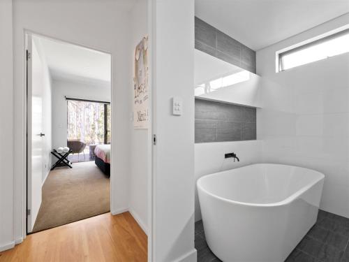 a bathroom with a white tub and a bedroom at Tall Trees Margaret River in Margaret River Town