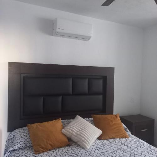 a bedroom with a black headboard and two pillows on a bed at Hermosa Casa en Orilla del lago -Zona de villedos- in San Cristóbal Zapotitlán