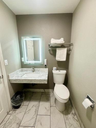 a bathroom with a toilet and a sink and a mirror at Villa Court Inn Oroville in Oroville