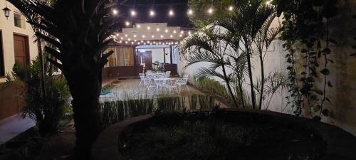 a patio with white tables and a tree and lights at Hotel Sansivar in El Venado