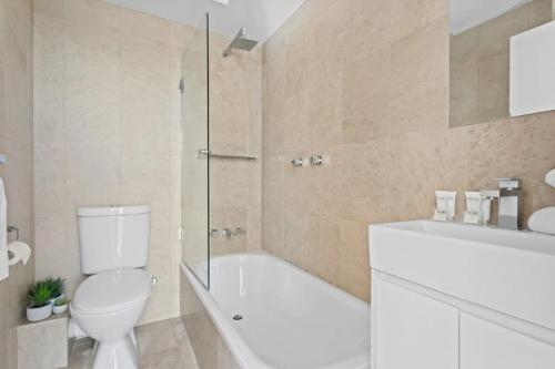a bathroom with a toilet and a tub and a sink at Prime Location 2-Bed Apartment with Parking in Sydney