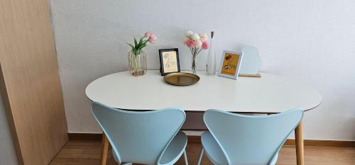 una mesa blanca con 2 sillas y un jarrón de flores en Hongdae Guesthouse3 1min from Hongik Uni station Exit #1, en Seúl