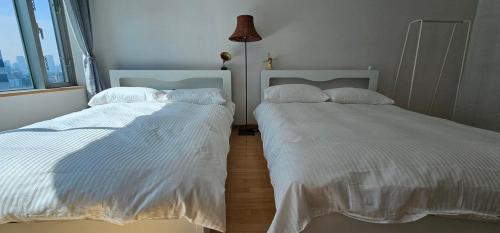 dos camas sentadas una al lado de la otra en un dormitorio en Hongdae Guesthouse3 1min from Hongik Uni station Exit #1, en Seúl
