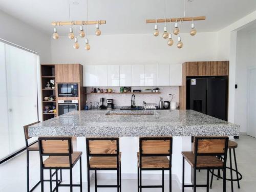 une cuisine avec un grand îlot avec des chaises de bar dans l'établissement Espectacular casa frente al mar 1era fila con piscina privada, à Asia