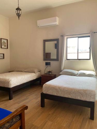 a bedroom with two beds and a mirror and a window at Grann Posada Xilitla in Xilitla