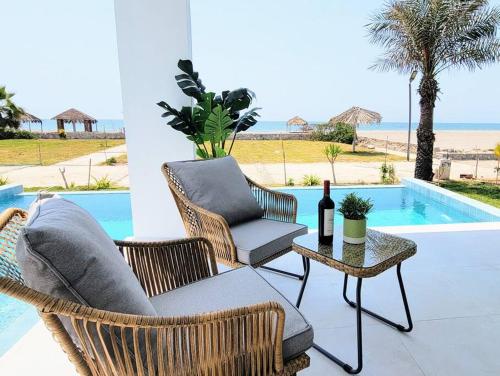 - une terrasse avec des chaises et une table avec une bouteille de vin dans l'établissement Espectacular casa frente al mar 1era fila con piscina privada, à Asia