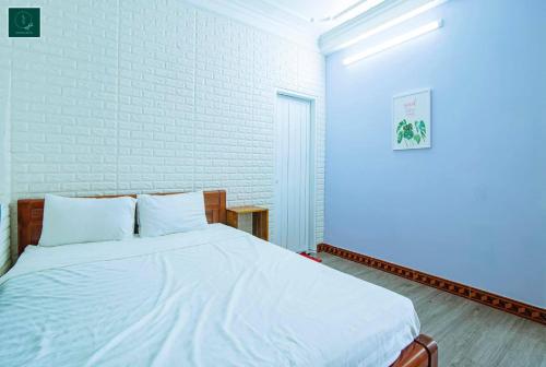ein Schlafzimmer mit einem Bett mit weißer Bettwäsche und einer Ziegelwand in der Unterkunft SAMI Coffee Hotel in Dong Hoi