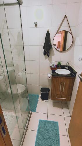 une salle de bain avec une douche, un lavabo et un miroir dans l'établissement Cantinho Sol & Mar Pé na Areia frente ao Mar com churrasqueira na sacada e piscina, à Praia Grande