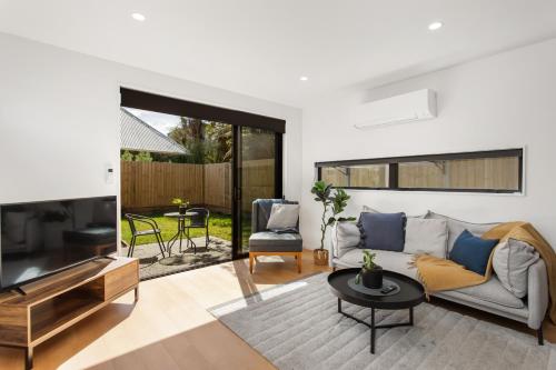 a living room with a couch and a television at Stylish New 8 Mins CBD Free Parking in Christchurch