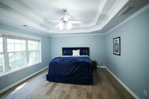 a blue bedroom with a bed and a ceiling fan at Big 5 Bdrm Private Hot Tub Pool Table Near Shops in Loganville