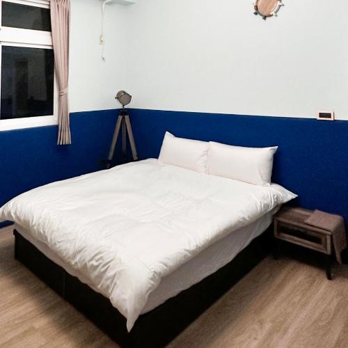 a bed in a room with a blue wall at 虎尾慢遊 in Huwei