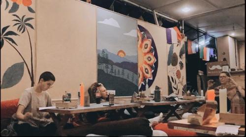 a group of people sitting at tables in a room at One More Night hostel and community living in McLeod Ganj