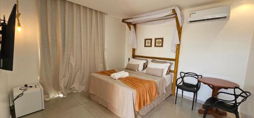 a bedroom with a bed and a table and chairs at Pousada Alkamar Quarto comfort in Maragogi
