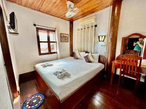 a bedroom with a bed with a table and a mirror at Rattana Guesthouse in Luang Prabang