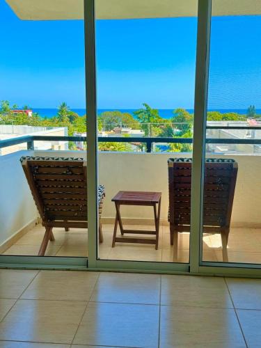 a balcony with two benches and a table and the ocean at El más completo, a menos de 5 minutos de la playa, free wifi fuera del alojamiento in San Felipe de Puerto Plata