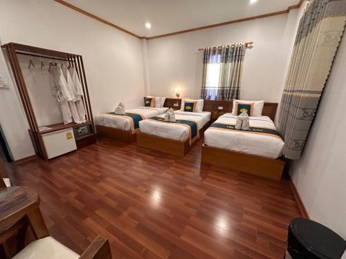 three beds in a room with wooden floors at Villa Mahasok hotel in Luang Prabang