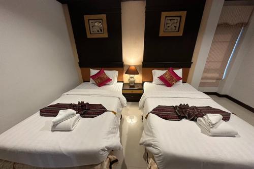 two beds in a hotel room with white sheets at Chiangrai Grand Room Hotel in Chiang Rai