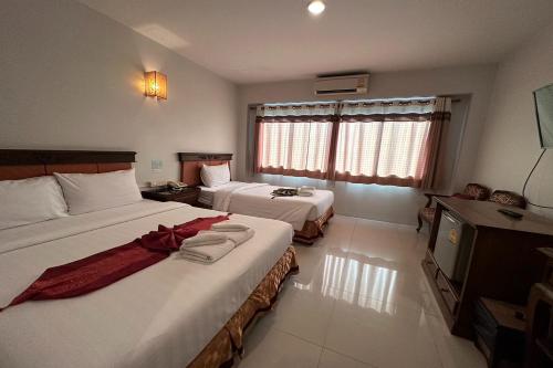 a hotel room with two beds and a television at Chiangrai Grand Room Hotel in Chiang Rai