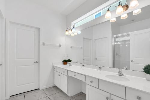 ein weißes Badezimmer mit zwei Waschbecken und einem großen Spiegel in der Unterkunft Luxury Home at Sonoma 9 En-suites SON102 in Kissimmee