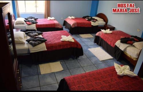 Habitación con 4 camas con sábanas rojas y blancas. en Hostal Maria José, en Baños