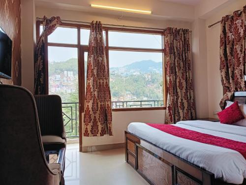 a bedroom with a bed and a large window at ASTON HOME STAY in Chhota Simla