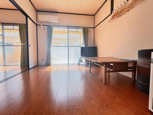 a living room with a table and a wooden floor at Lit 天草 in Amakusa