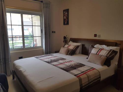 a large bed in a bedroom with a window at FOKUZZY LODGE in Accra