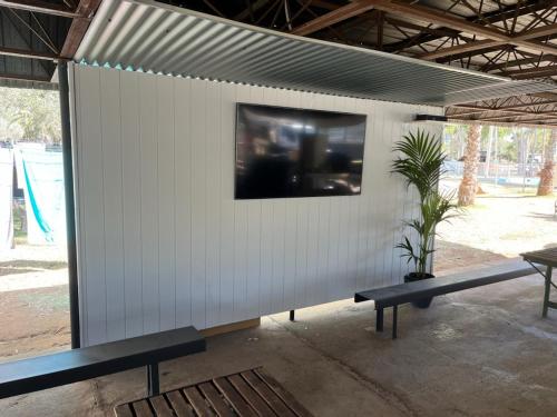 Una pared blanca con dos bancos y una TV. en Heritage Caravan Park en Alice Springs