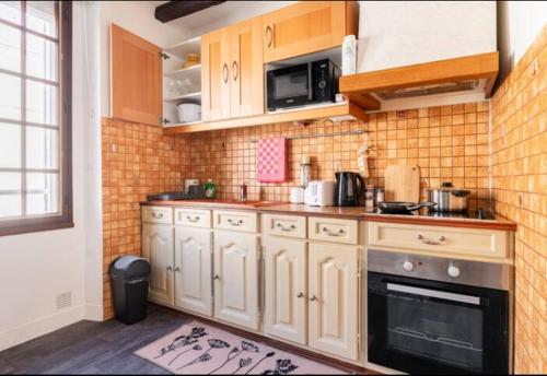 a kitchen with white cabinets and a stove at Appartement 2 pièces 36m2, CDG Airport, Disneyland Paris, Asterix, Parc des expo, 10min gare de Chelles, Parking gratuit dans la ville in Le Pin