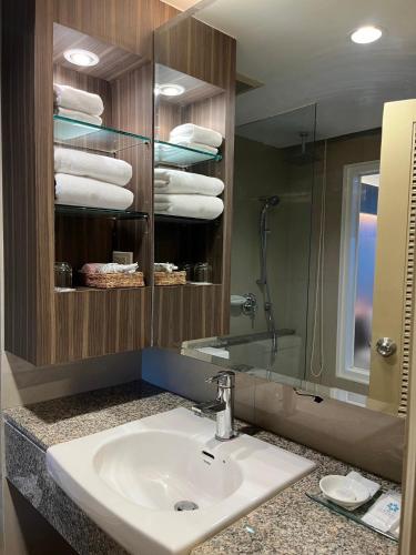 a bathroom with a sink and a mirror and towels at Suntara Wellness Resort & Hotel in Chachoengsao