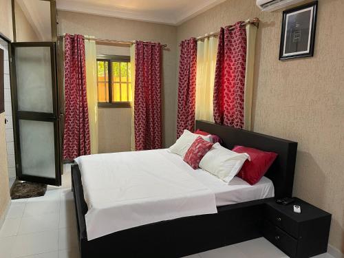a bedroom with a bed with red and white pillows at LGH (Luxury Guest House) Résidence in Lomé