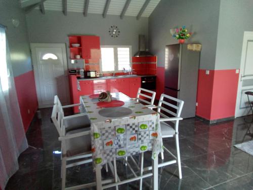 a kitchen with red cabinets and a table and chairs at Villa LANDREVA in Anse-Bertrand