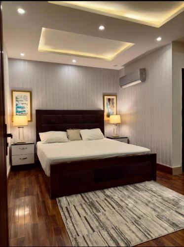 a bedroom with a large bed with two night stands and two lamps at 1 bed apartment available in Al nadd in Sharjah