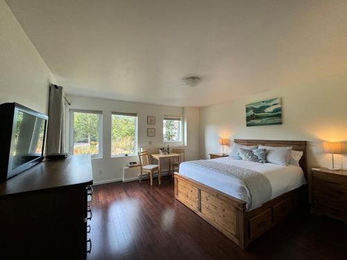 a bedroom with a bed and a desk with a television at Liahona Guest House in Ucluelet