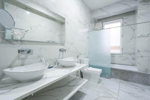 a white bathroom with two sinks and a toilet at Dey Ngyam Boutique in Geylegphug