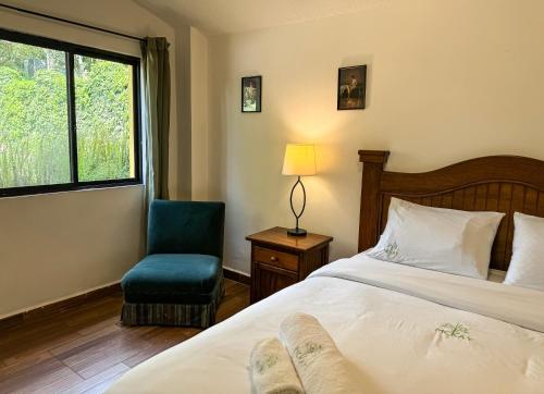 a bedroom with a bed and a chair and a window at Mckay's Quinta in Yaruqui
