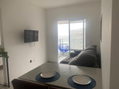 uma sala de estar com uma mesa e um sofá em Frente ao Mar, Sacada e Garagem em Solemar