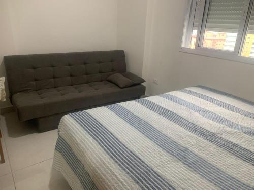 uma cama e um sofá num quarto em Frente ao Mar, Sacada e Garagem em Solemar