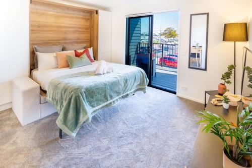 a bedroom with a bed and a balcony at City Living: Upper Studio Haven on Wilmer in Christchurch