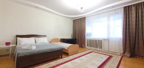 a bedroom with a bed and a window and a rug at 9 спальных мест в центре 3х комн кв с 4мя кроватями и 2мя санузлами с шикарным видом на Байтерек in Astana