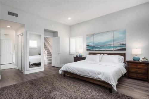 um quarto branco com uma cama grande e uma escada em Steps to the beach, piers, downtown em Huntington Beach