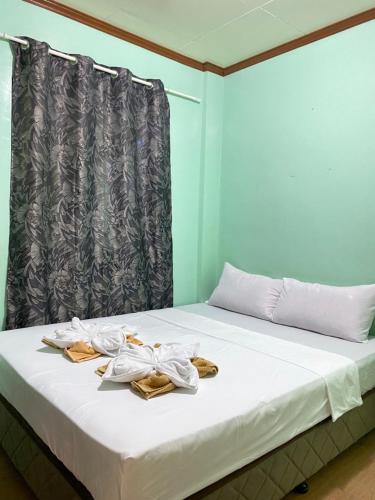 Una cama con toallas y una cortina en MILA'S GUESTHOUSE, en Basdiot