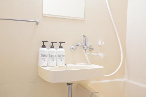 a bathroom sink with three bottles on it at walk to JR Shibuya sta.-QoE2 in Tokyo