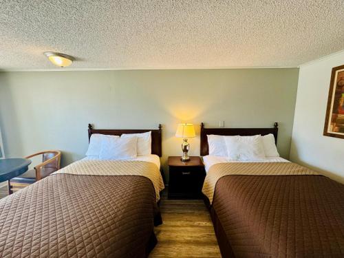 a hotel room with two beds and a table with a lamp at Knights Inn Bridgeport Frankenmuth in Bridgeport