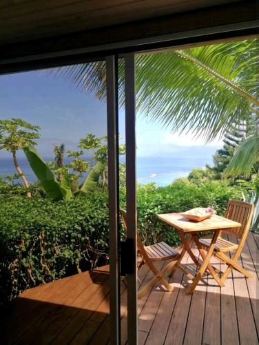 una mesa y sillas en una terraza con vistas al océano en Bungalow Moemoea, en Punaauia