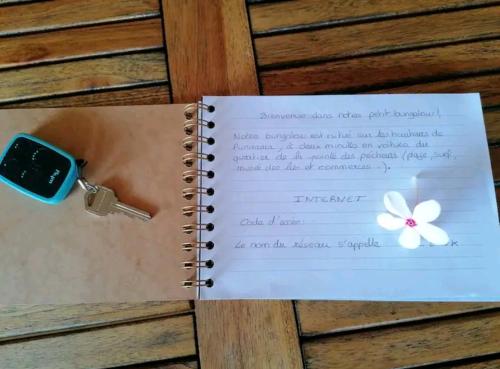 普納奧亞的住宿－Bungalow Moemoea，一本笔记本,上面有一把钥匙和一朵花